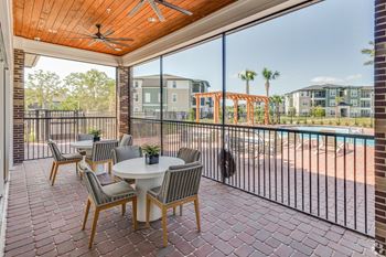 A patio with a table and chairs overlooking a pool.